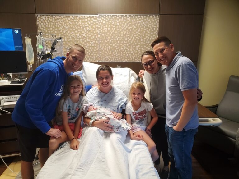 iowa surrogate mother holding surrogate baby and accompanied by new parents and her family