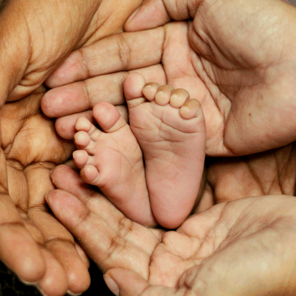 surrogate mother and parent via surrogacy holding newborn baby's feet