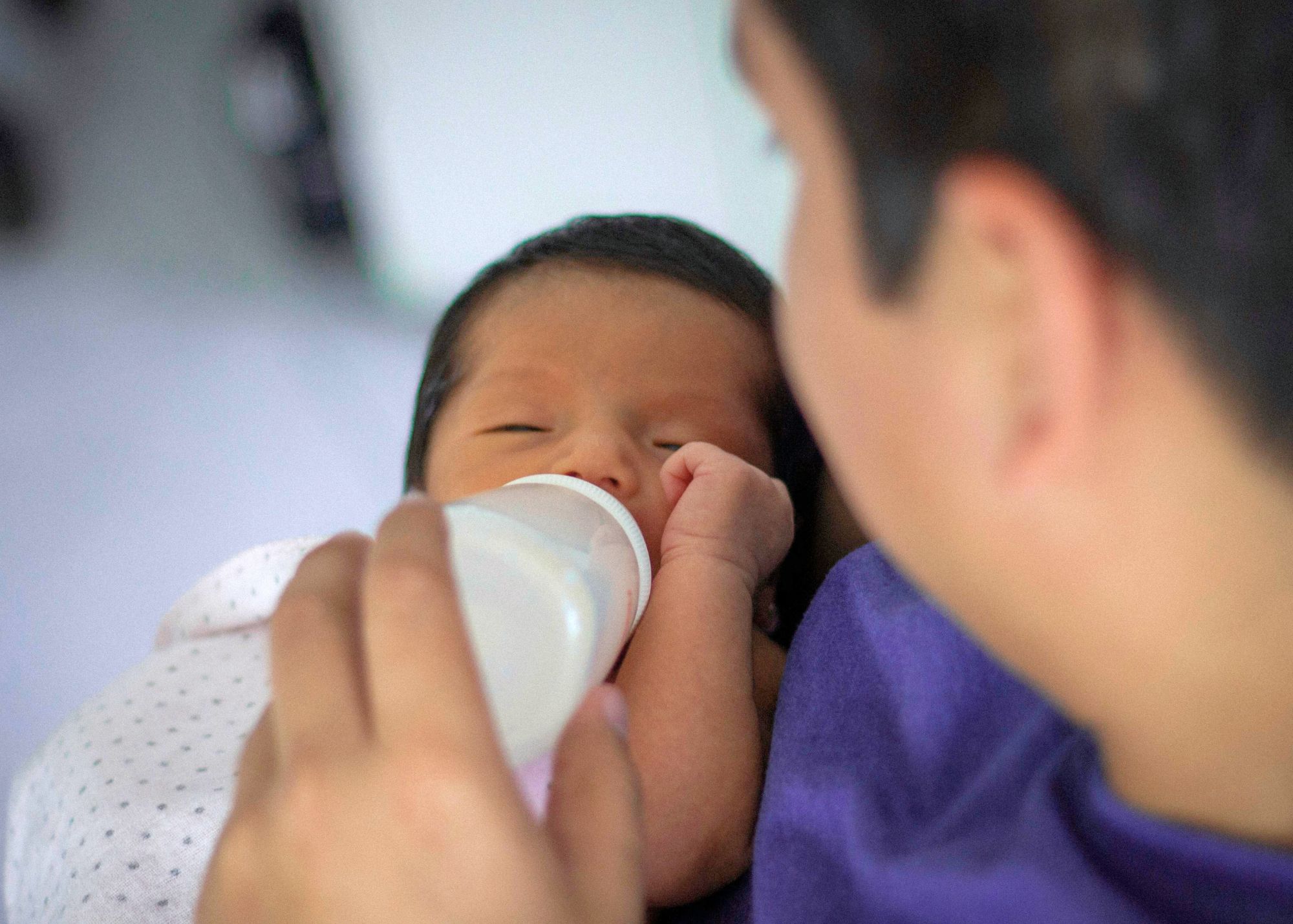hispanic father bottle feeding baby born via surrogacy