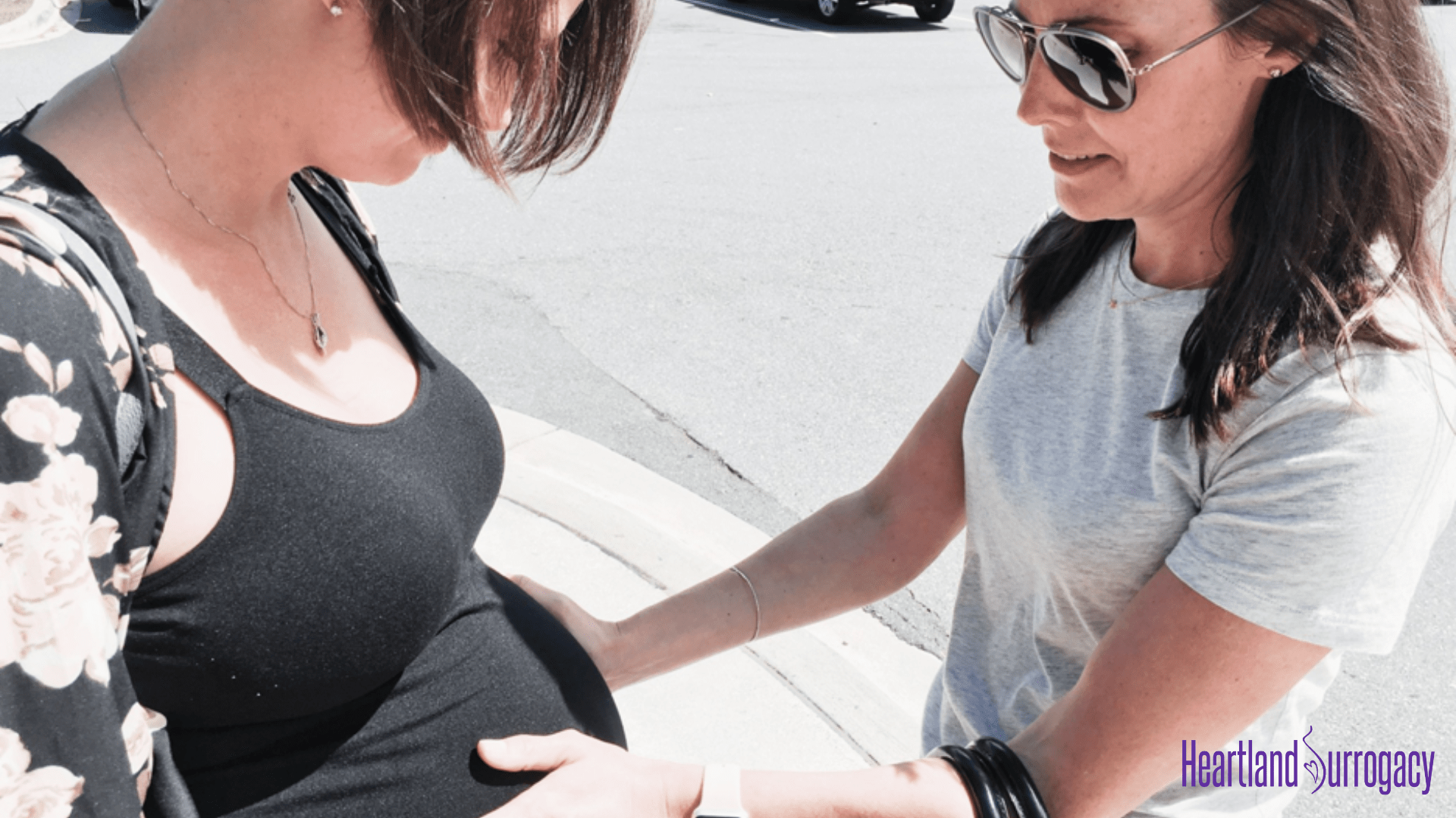 surrogate mother with baby belly held by intended mother